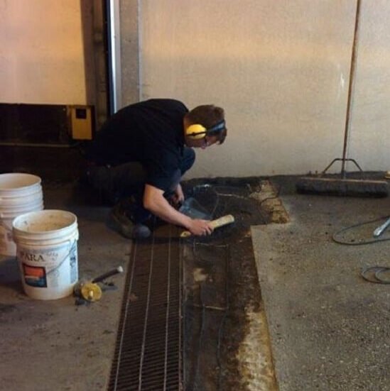 Electrician preparing damaged heating cables in a parking garage ramp for repairs.